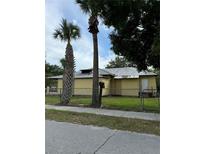Charming single-story home with yellow siding, mature trees, and a quaint yard at 585 Washington St, New Smyrna Beach, FL 32168