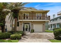 Two-story home with a balcony, garage, and a front yard featuring lush landscaping and mature palm trees at 6956 Turtlemound Rd, New Smyrna Beach, FL 32169
