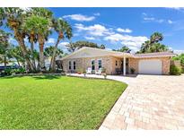 Charming single-story stone home featuring a lush front lawn and brick-paved driveway at 22 Sand Dune Dr, New Smyrna Beach, FL 32169