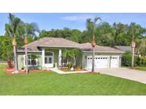 Charming single-story home features a three-car garage, manicured lawn, and mature palm trees at 3288 Spruce Creek Gln, Port Orange, FL 32128
