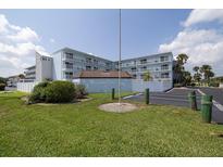 Beautiful condo building with well-manicured lawn, lush vegetation, and ample parking in a prime location at 3700 S Atlantic Ave # 108, New Smyrna Beach, FL 32169
