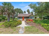 Charming home featuring a bright orange door and a delightful red bridge in its landscaped front yard at 807 Craig St, New Smyrna Beach, FL 32168