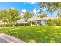 Charming home featuring a well-manicured lawn, lush landscaping, and a light blue exterior at 904 Clubhouse Blvd, New Smyrna Beach, FL 32168