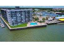 Expansive aerial view of harborside apartment building with swimming pool and boats docked nearby at 101 N Riverside Dr # 1090, New Smyrna Beach, FL 32168