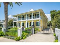 Stately two-story yellow home with white columns, balconies, dark shutters, iron gate and manicured lawn at 1212 S Riverside Dr, New Smyrna Beach, FL 32168