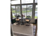 Enclosed patio area with decorative table and chairs overlooking a peaceful pond and lush landscaping at 3552 Casalta Cir, New Smyrna Beach, FL 32168