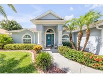 Charming home entrance with blue door, rocking chairs, and lush, colorful landscaping in a well maintained yard at 406 Phillips Creek Ln, New Smyrna Beach, FL 32168