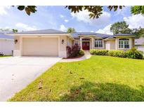 Charming single-story home with a well-manicured lawn, inviting curb appeal, and attached two-car garage at 6065 Spruce Point Cir, Port Orange, FL 32128