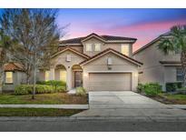 Two-story house with a beige exterior, two-car garage, and landscaping at 5244 Oakbourne Ave, Davenport, FL 33837