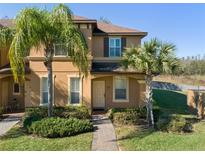 Tan two-story townhome with palm trees, brick walkway, and well-manicured landscaping at 3204 Calabria Ave # 443, Davenport, FL 33897