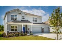 Two-story house with gray siding, stone accents, and a two-car garage at 14 Weston Rd, Leesburg, FL 34748