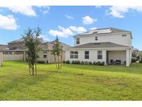 Spacious backyard with a covered patio, well-maintained lawn, and solar panels at 224 Trinity Ridge Cir, Davenport, FL 33897