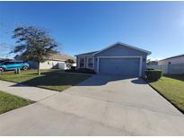 Single-story home with gray exterior, two-car garage, and landscaped yard at 1080 Condor Dr, Haines City, FL 33844