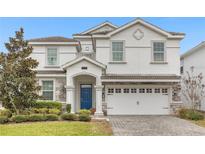 Two-story house with white exterior, gray stone accents, and a three-car garage at 1539 Flange Dr, Davenport, FL 33896