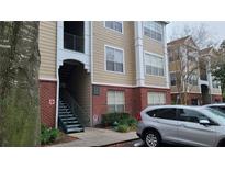 Tan building exterior with red brick accents and green stairs leading to upper units for easy access at 13103 Mulberry Park Dr # 824, Orlando, FL 32821