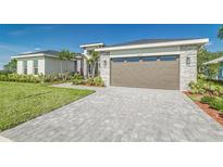 Beautifully landscaped home featuring a paver driveway leading to a two-car garage at 839 Waterfern Trail Dr, Auburndale, FL 33823