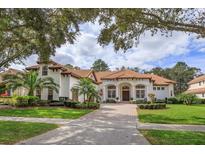 Beautiful two-story home with a tile roof, lush landscaping, and a brick paved driveway at 6130 Blakeford Dr, Windermere, FL 34786