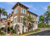 Tan three-story townhome with a Spanish-style roof and lush landscaping at 637 Pavia Loop, Lake Mary, FL 32746