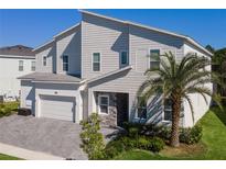 Two-story home with light-grey siding, stone accents, and a two-car garage at 1758 Oak Blossom Dr, Davenport, FL 33837