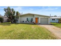 Charming ranch home with a well-manicured lawn and orange door at 36 Camellia Dr, Ormond Beach, FL 32176