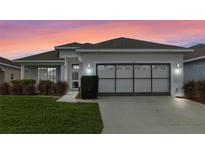 Single-story home with gray garage door and landscaped lawn at 145 Lewis Dr, Davenport, FL 33837