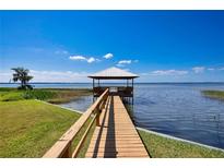 Picturesque waterfront view of a private dock with a covered gazebo on a sunny day at 2205 Cypress Cove Dr, Tavares, FL 32778