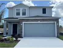 Two-story home with a stone accent garage, well-manicured landscaping, and a concrete driveway at 5583 Maddie Dr, Haines City, FL 33845