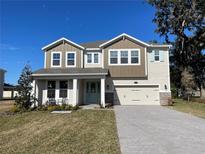 Two-story house with light brown and beige siding, light blue door, and a paved driveway at 124 Lake Dr, Oviedo, FL 32765