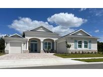 Charming home with stone accents, blue shutters, well-manicured lawn, and stylish architectural details at 3962 Kennebunk Loop, Mount Dora, FL 32757