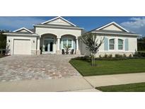 Charming single-story home featuring a light gray exterior, a paved driveway and light blue shutters at 3962 Kennebunk Loop, Mount Dora, FL 32757