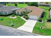 Home featuring an attached garage, meticulously maintained lawn, and vibrant flower beds at 2172 Nw 50Th Cir, Ocala, FL 34482