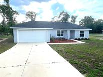 Charming single-story home boasts a well-manicured lawn and a concrete driveway leading to an attached garage at 2 Fisher Lane Way, Ocklawaha, FL 32179