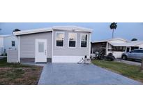 Gray manufactured home with white door and windows, golf cart, and car in driveway at 9000 Us Highway 192 # Lot 316, Clermont, FL 34714