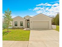 Tan house with a two-car garage and landscaping at 6360 Chorus Dr, Mascotte, FL 34753