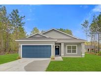 Charming single Gathering home boasts a blue garage door, green lawn, and freshly painted exterior at 95 Malauka Place Trak, Ocklawaha, FL 32179