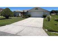 House exterior featuring a large driveway and well-maintained lawn at 517 Cardinal Dr, Kissimmee, FL 34759