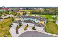Aerial view of a four-unit townhome community with attached garages and a golf course view at 880 Driving Range Ct, Reunion, FL 34747