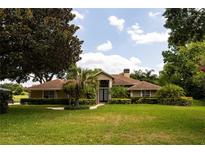 Tan one-story house with brown roof, manicured lawn, and lush landscaping at 2119 Willow Brick Rd, Windermere, FL 34786