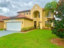 Charming two-story home with a manicured lawn, arched entryway and lush landscaping at 3044 Camino Real S Dr, Kissimmee, FL 34744