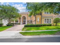Stately two-story home featuring a symmetrical design, arched windows, and a brick driveway, nestled among mature trees at 334 Chadwick Dr, Davenport, FL 33837