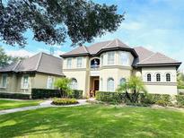 Charming two-story home with a well-manicured lawn, tiled roof, and a second story balcony at 8734 Crestgate Cir, Orlando, FL 32819