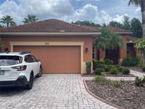 Home exterior featuring a red tile roof, brick driveway, and well-maintained landscaping at 681 Coronado Dr, Kissimmee, FL 34759