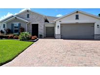 Charming single-story home featuring a brick driveway, manicured lawn, stone accents, and a two-car garage at 840 Jasmine Creek Rd, Kissimmee, FL 34759