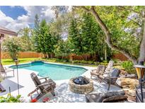 Inviting backyard with a sparkling pool, lush landscaping, and a cozy fire pit area for outdoor enjoyment at 4016 Salmon Dr, Orlando, FL 32835