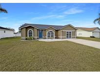 Tan one-story house with a blue door and landscaping at 7856 Habersham Dr, Lakeland, FL 33810