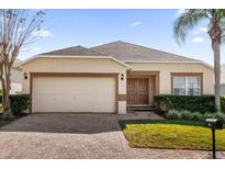 One-story house with beige exterior, brown accents, and a two-car garage at 313 Kensington Dr, Davenport, FL 33897