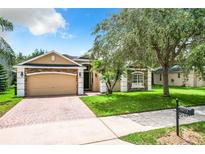 Charming single-Gathering home showcasing a well-maintained lawn, brick driveway, and a stone-accented facade at 3872 Heirloom Rose Pl, Oviedo, FL 32766