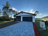 Charming home featuring a modern white and black color scheme, brick driveway, and manicured lawn at 1102 East Pkwy, Deland, FL 32724