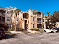 Condo building exterior featuring landscaping, stairs to upper floors, and multiple parking spaces at 3224 Dante Dr # 108, Orlando, FL 32835