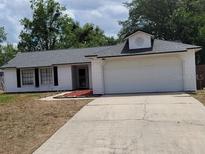 Charming one-story home featuring a two-car garage, white siding, black shutters, and a well-maintained front lawn at 2495 Sedgefield Ave, Deltona, FL 32725